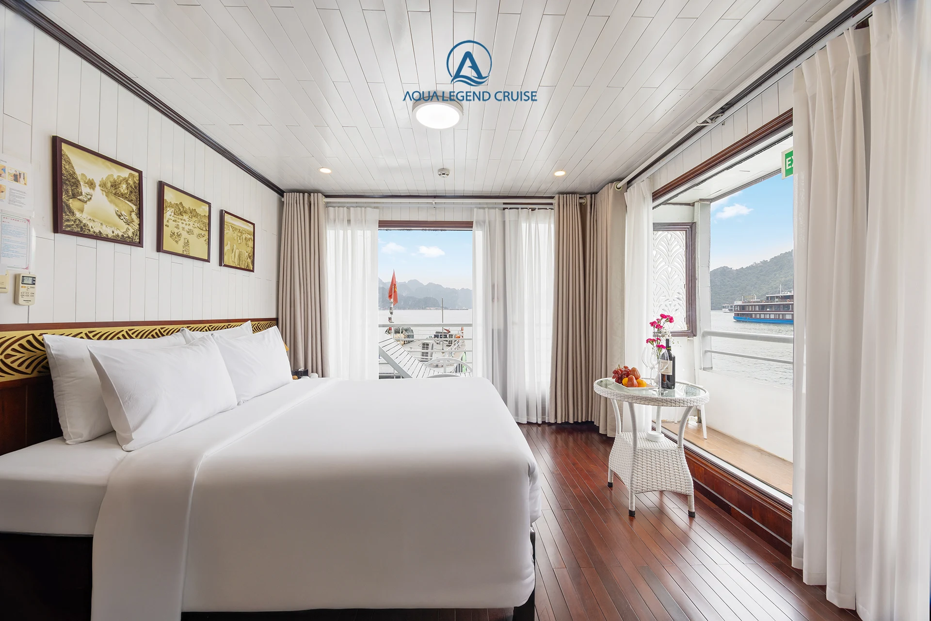 Queen Suite Balcony cabin with a double bed and corner windows on Aqua Legend Cruise
